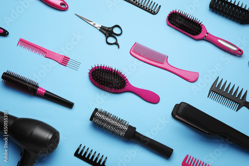 Flat lay composition of professional hairdresser tools on light blue background