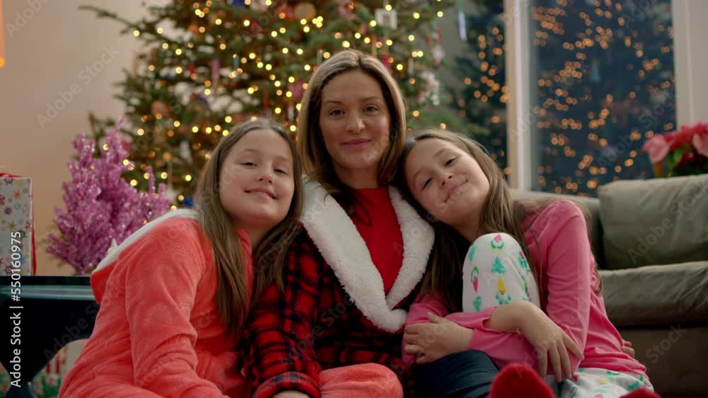 Portrait of a mother and daughters smiling in front of a Christmas tree
