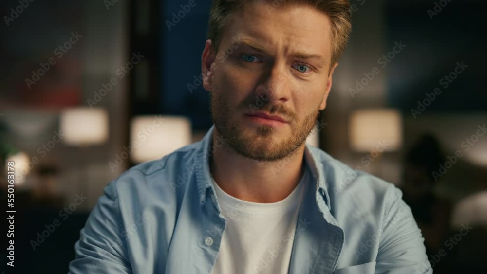 Closeup serious guy ending call at evening flat. Man watching wife rejoicing Closeup serious guy ending call at evening flat. Man watching wife rejoicing