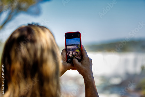 Woman takes a picture of the Iguazu Falls photo