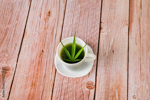 Hot Cannabis herbal tea and marijuana leaves on wooden table. photo