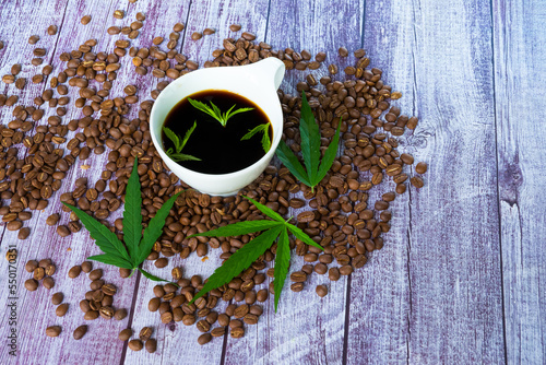 A cup of coffee cannabis with Marijuana leaves and coffee beans on wooden table. photo