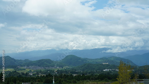 The harvesting yellow rice field view located in the valley among the mountains with the cloudy sky as background