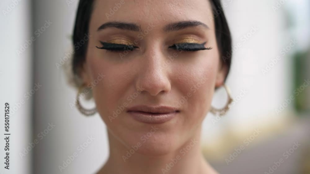 Close-up face of beautiful woman with black hair and long eyelashes opening brown eyes looking at camera. Gorgeous confident dancer posing getting ready for Indian dance outdoors Close-up face of beautiful woman with black hair and long eyelashes opening brown eyes looking at camera. Gorgeous confident dancer posing getting ready for Indian dance outdoors