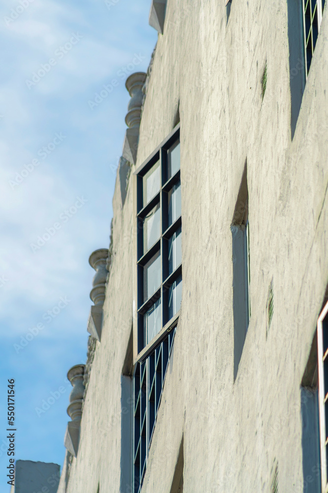 Close up of open window on exterior of modern apartment building with blue and white gradient sky in sun midday Close up of open window on exterior of modern apartment building with blue and white gradient sky in sun midday