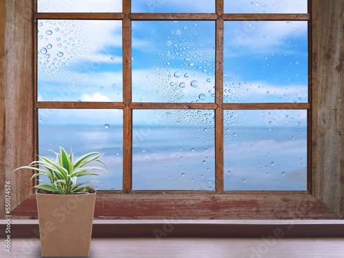 On a rainy day  water droplets were visible on the outside glass blurred.  Window background  The brown wooden floor on the left has a plant pots.