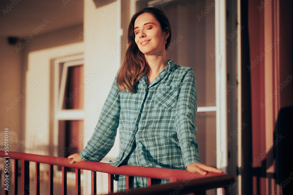 Happy Woman Standing in a Balcony Enjoying her Morning. Carefree morning person feeling well rested and relaxed
