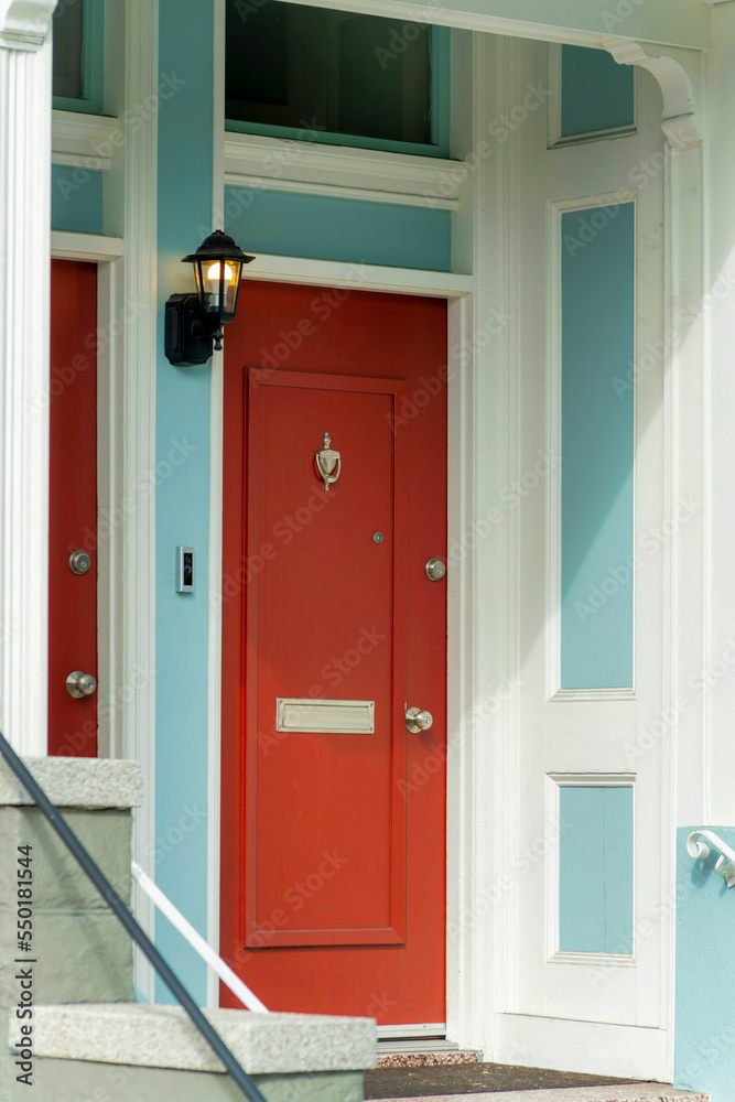 Red front door on modern doorstep in the neighborhood in downtown major city with white accent paint and blue Red front door on modern doorstep in the neighborhood in downtown major city with white accent paint and blue