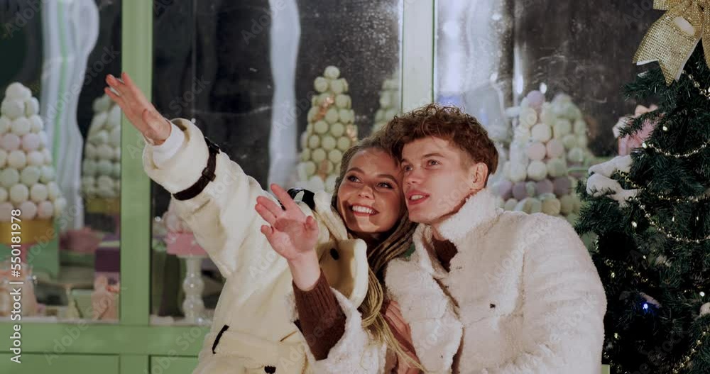 Happy couple looking away to sky star while sitting outside store. Man and woman are day dreaming while spending leisure time together. They are enjoying Christmas at night. Happy couple looking away to sky star while sitting outside store. Man and woman are day dreaming while spending leisure time together. They are enjoying Christmas at night.