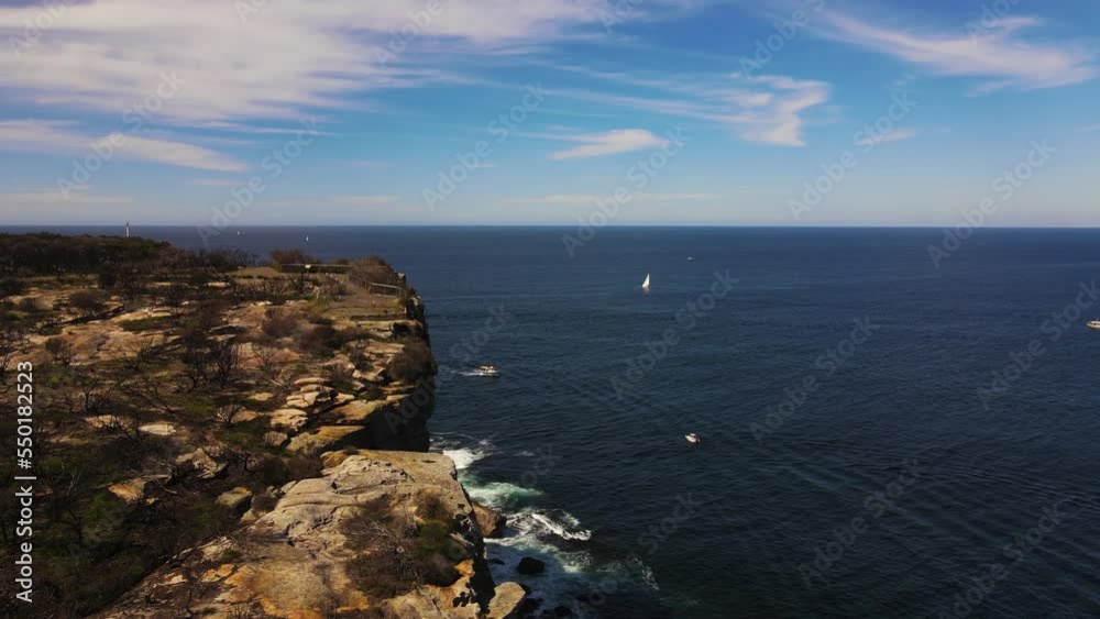 Sheer rocks dropping off to boats in the sea drone shot Sheer rocks dropping off to boats in the sea drone shot