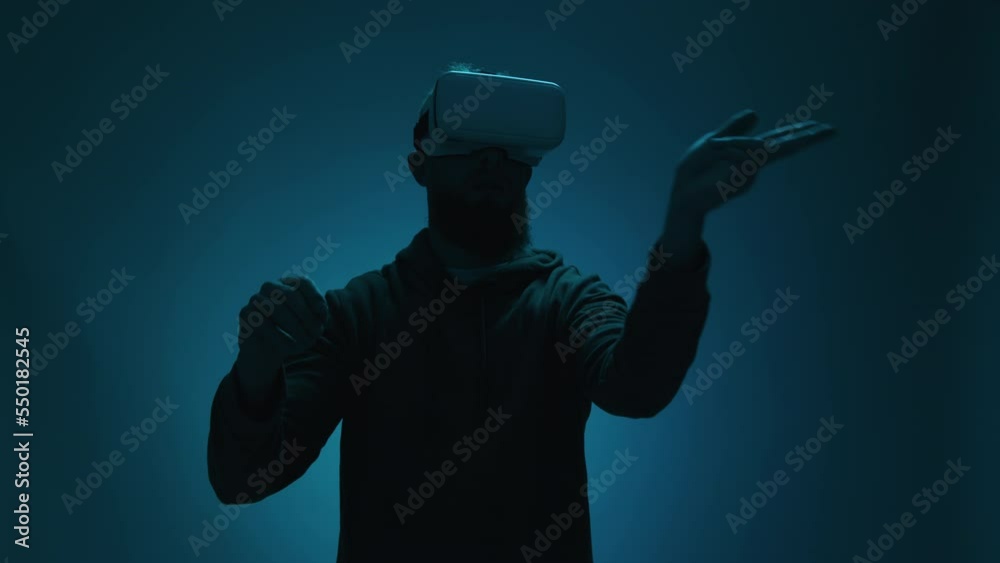 Portrait of a man wearing a VR glasses in the dark room. Tall, caucasian guy testing technology program against bluish neon background. High quality 4k footage Portrait of a man wearing a VR glasses in the dark room. Tall, caucasian guy testing technology program against bluish neon background. High quality 4k footage