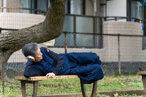 公園のベンチで寝るシニア男性 photo