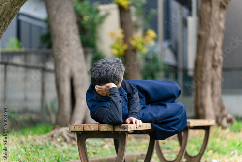 公園のベンチで寝るシニア男性 © metamorworks