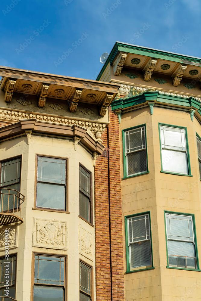 Two exterior bay window spires on side of modern brown stone building with flat roofs and decorative paint Two exterior bay window spires on side of modern brown stone building with flat roofs and decorative paint