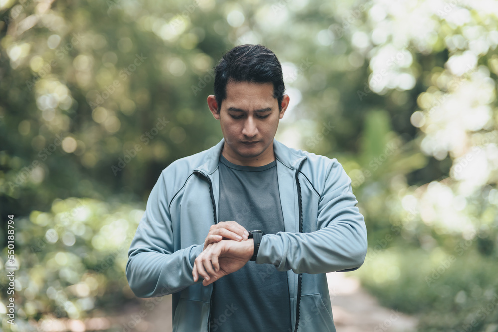 sport man checking at smartwatch during training and running in the park. Outdoor workout, Healthy lifestyle concept. sport man checking at smartwatch during training and running in the park. Outdoor workout, Healthy lifestyle concept.
