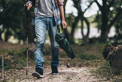 Hikers use trekking pole with backpacks and hold tent bag walking through the forest. hiking and adventure concept.