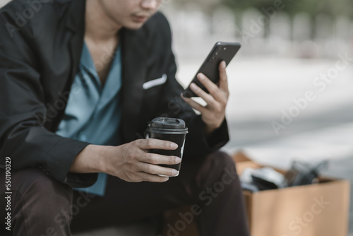 Employees fired or resigned from the company hold hot cup of coffee and using their mobile phones to search for jobs..Unemployed, hiring job, quitting job concept.