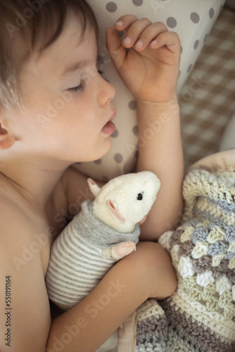 Little sweet cute baby sleeps in his bed with a toy.