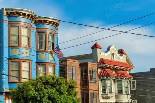 Three decorative houses with blue and red and white colors on the exterior and visible power lines and front yard trees