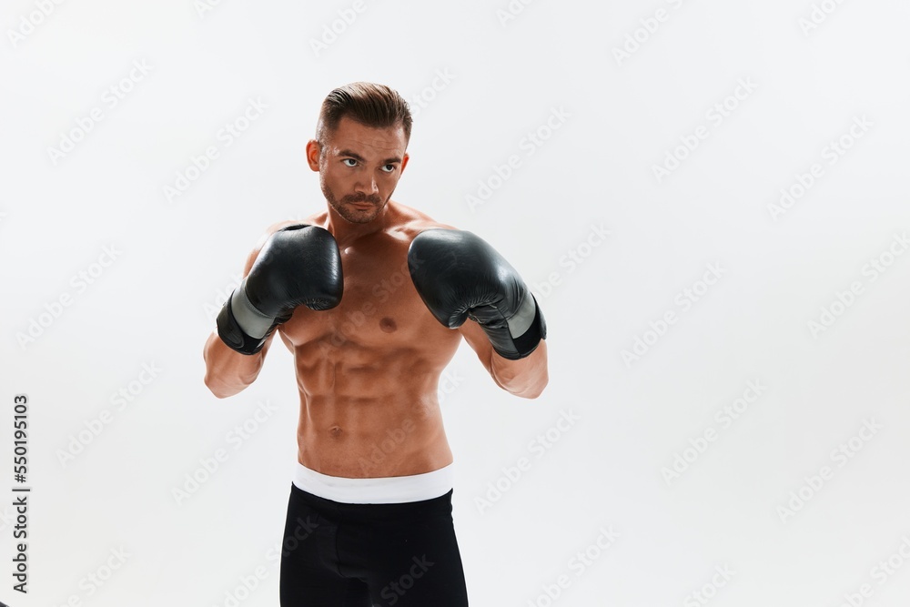 Man athletic bodybuilder poses in boxing gloves with nude torso abs in full-length background, boxing and martial arts. Advertising, sports, active lifestyle, competition, challenge concept. 