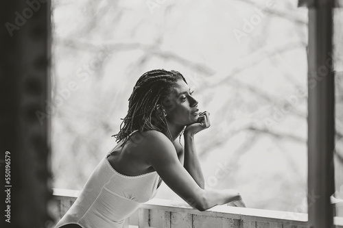Black and White picture of Black woman on patio smiling about the day