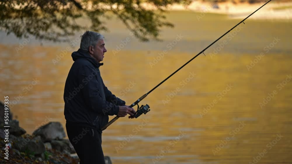 Senior man in jacket casts a spinning reel during fishing on a lake. Autumn fishing activity. Senior man in jacket casts a spinning reel during fishing on a lake. Autumn fishing activity.