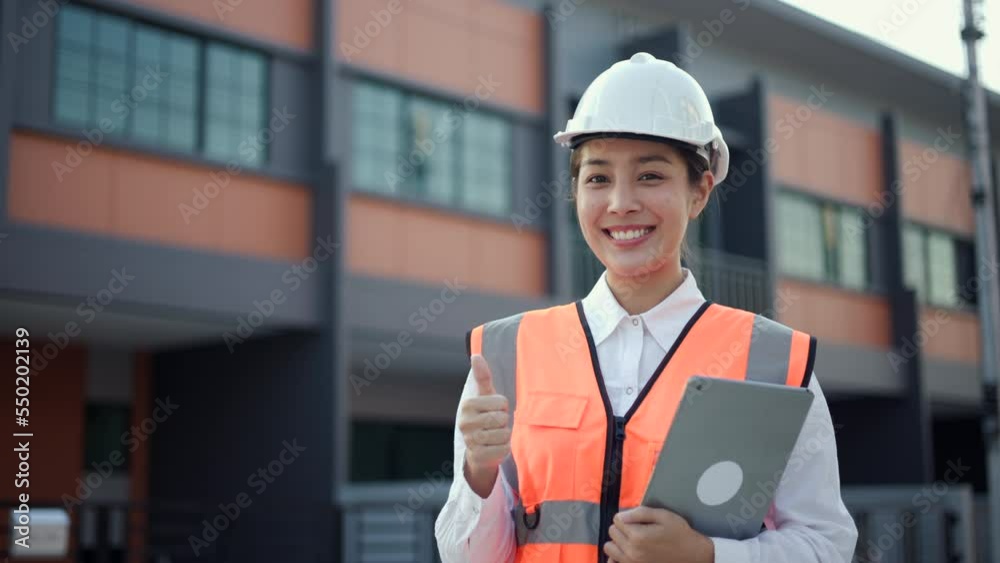 Serious engineer woman Using tablet for checking and maintenance to inspection at modern home building construction. Architect female looking forward with white safety helmet in construction site. Serious engineer woman Using tablet for checking and maintenance to inspection at modern home building construction. Architect female looking forward with white safety helmet in construction site.