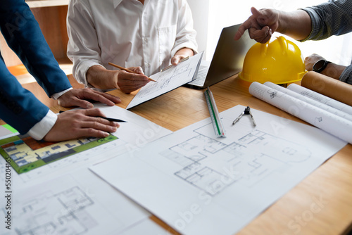 Businessman and architect meeting for planing and checking house design and house model and secretary takes notes, the architect design working drawing sketch plans blueprints