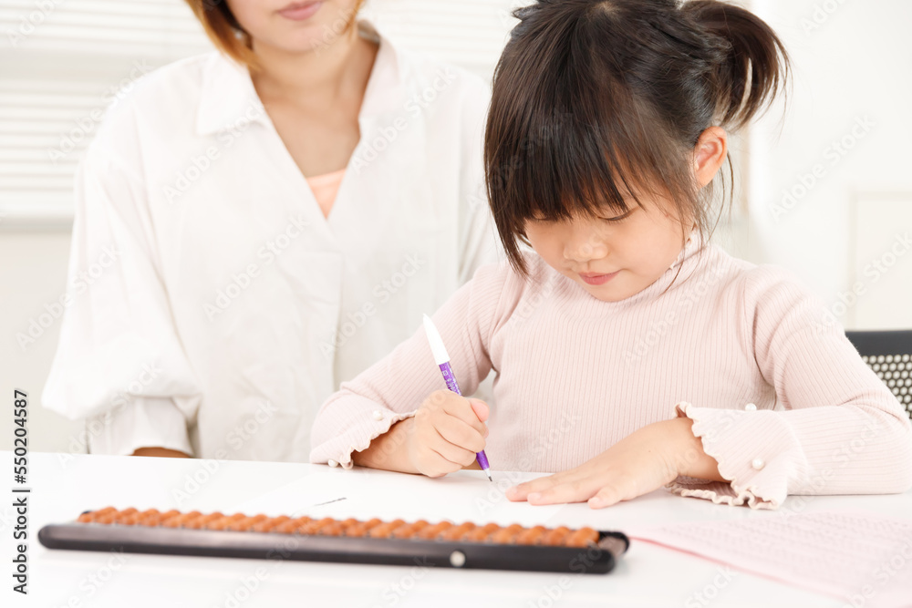 学習塾やそろばん教室の生徒の子供と先生。楽しく見守りながら子供を支援するイメージ。