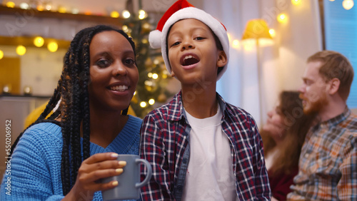 African-American woman and son in santa hat congratulating grandparents on christmas using video chat