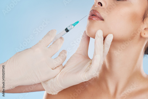 Botox, plastic surgery and filler with the lips of woman getting an injection with a syringe from the hands of a surgeon in gloves. Mouth, face and needle for beauty in studio on a blue background