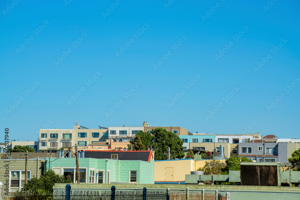 Row of houses and apartment building with decorative colors and copy space in blue sky background in midday sun