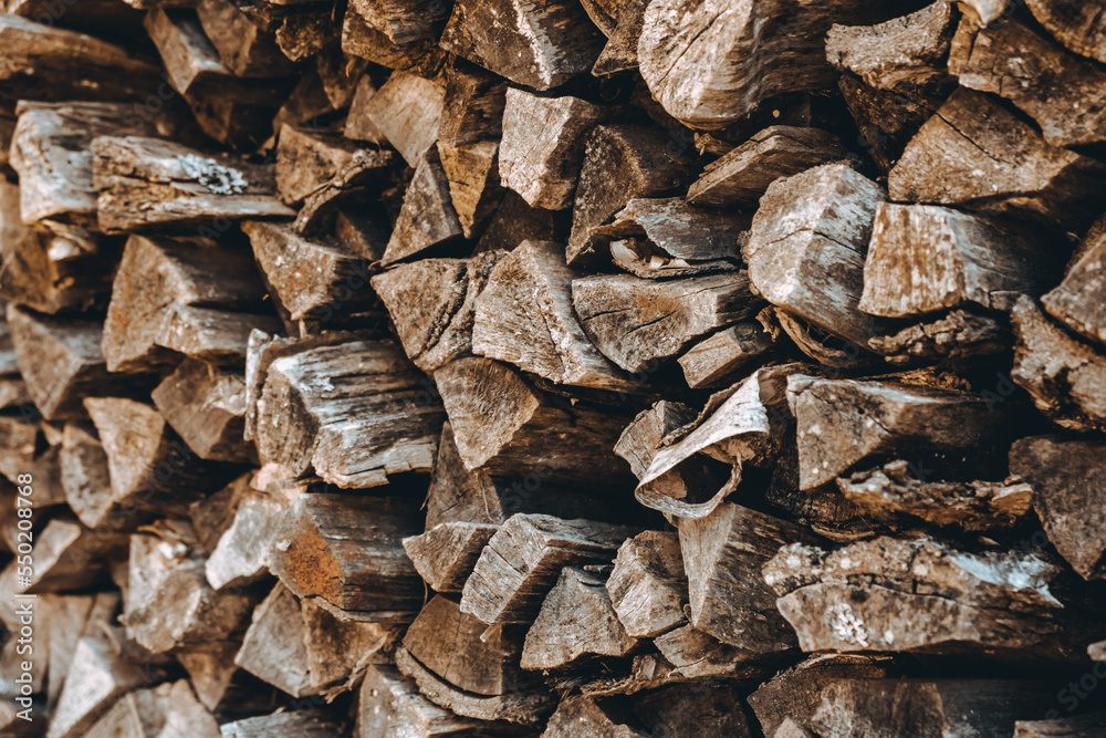 Chopped firewood pile. Woodpile wall. Heap of old dry pine woods. Brown textured background. Natural solid fuel resources. Winter preparation. Countryside pattern. Rustic style details. Woodworking