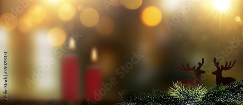 Weihnachtsbaum im Vordergrund vor einem unscharfen Wohnzimmer mit Kerzen