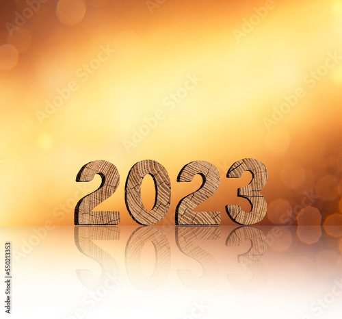 Jahreszahl 2023 aus Holz vor goldenem Hintergrund