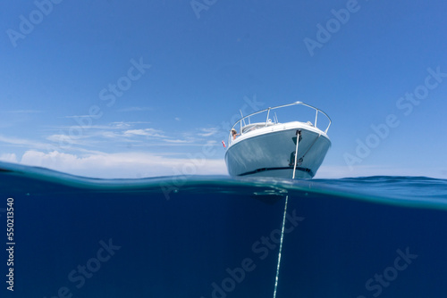 Fényképezés luxury boat sitting on anchor floating in deep blue water with blue sunny skies in background