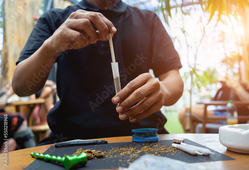 Fotografering Young man making cigarettes with medical marijuana