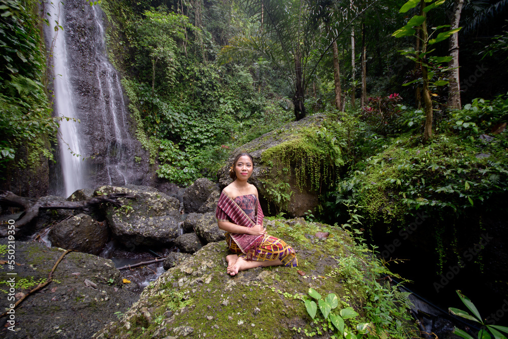 Girl in classic Balinese clothes pose at the Yeh Labuh waterfall