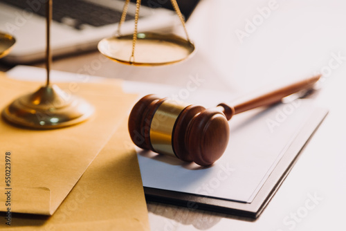 Justice and law concept.Male judge in a courtroom with the gavel, working with, computer and docking keyboard, eyeglasses, on table in morning light