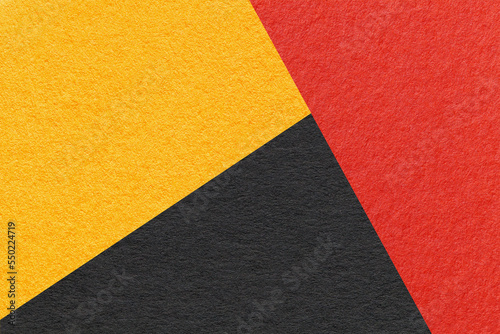 Craft black, red and yellow shade color paper background, macro. Vintage abstract golden cardboard