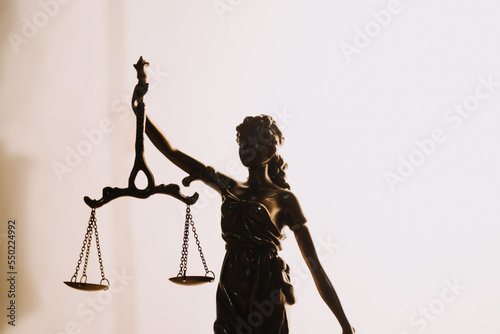 Justice and law concept.Male judge in a courtroom with the gavel, working with, computer and docking keyboard, eyeglasses, on table in morning light