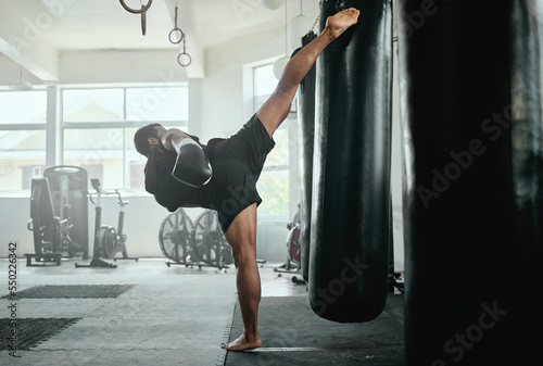 Professional, fit and active male fighter training with a punching bag in a gym. kickboxer practicing, training and fitness exercise for competitive fight, tournament or competition in a health club photo
