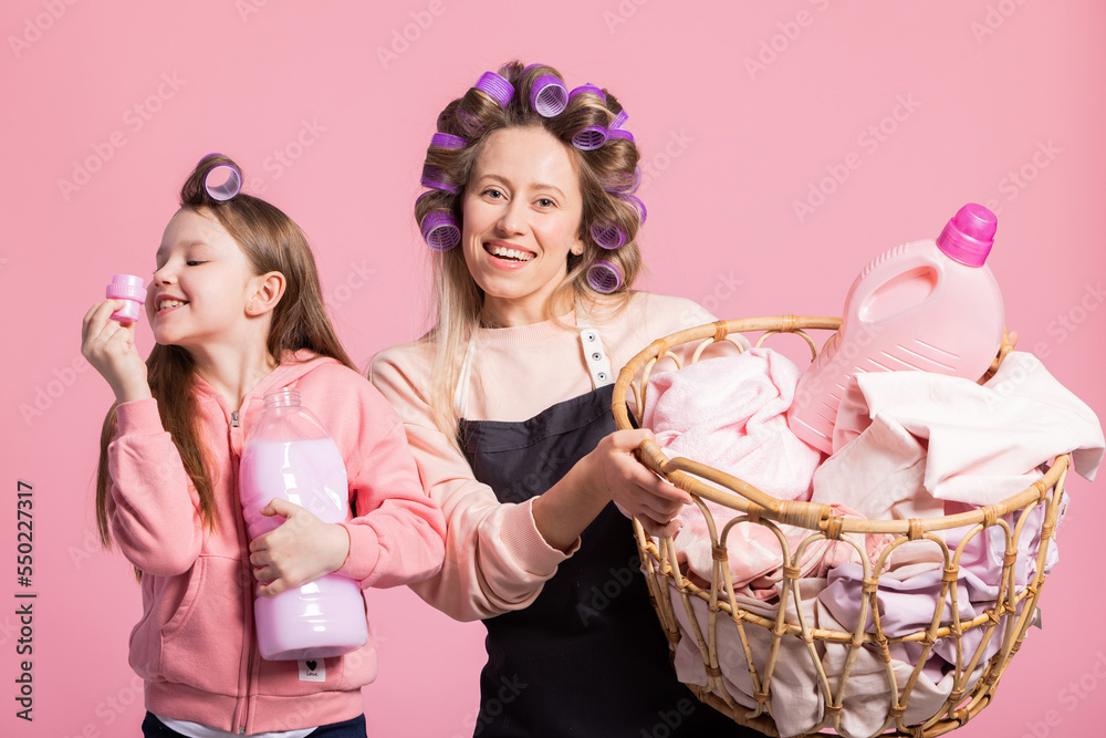 Smiling mother and daughter pose against pink background with a basket