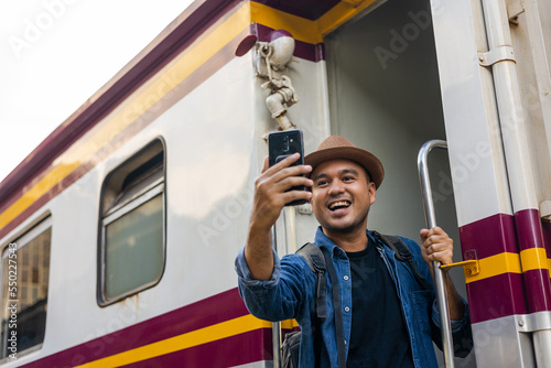 Canvastavla Freedom traveler young asian man hanging handrail on train and taking photo by smartphone