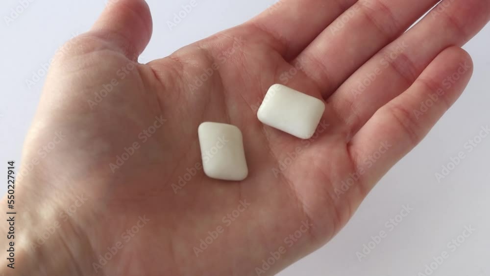 The woman opens her palm with two chewing gums in it. The girl gives him the gum.