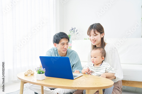 家で赤ちゃんとパソコンを見る両親