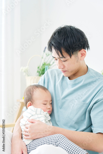 家で眠る赤ちゃんを抱っこする男性