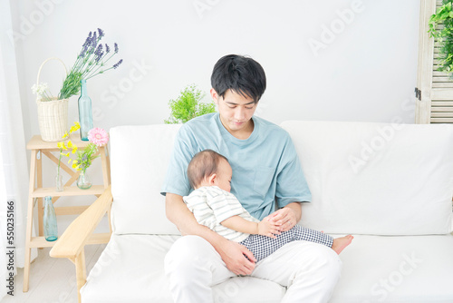 家で眠る赤ちゃんを抱っこする男性