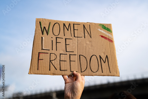 Demonstrator holding "Women, Life, Freedom" placard