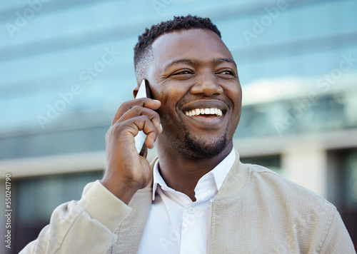 Man on a phone call outside a building in the street receiving news after winning online game. Happy guy getting corporate promotion at work. Winner excited about success and victory on smartphone.